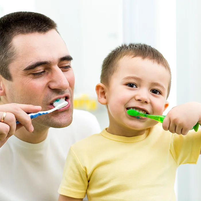 Un adulte et un enfant se brossent les dents ensemble